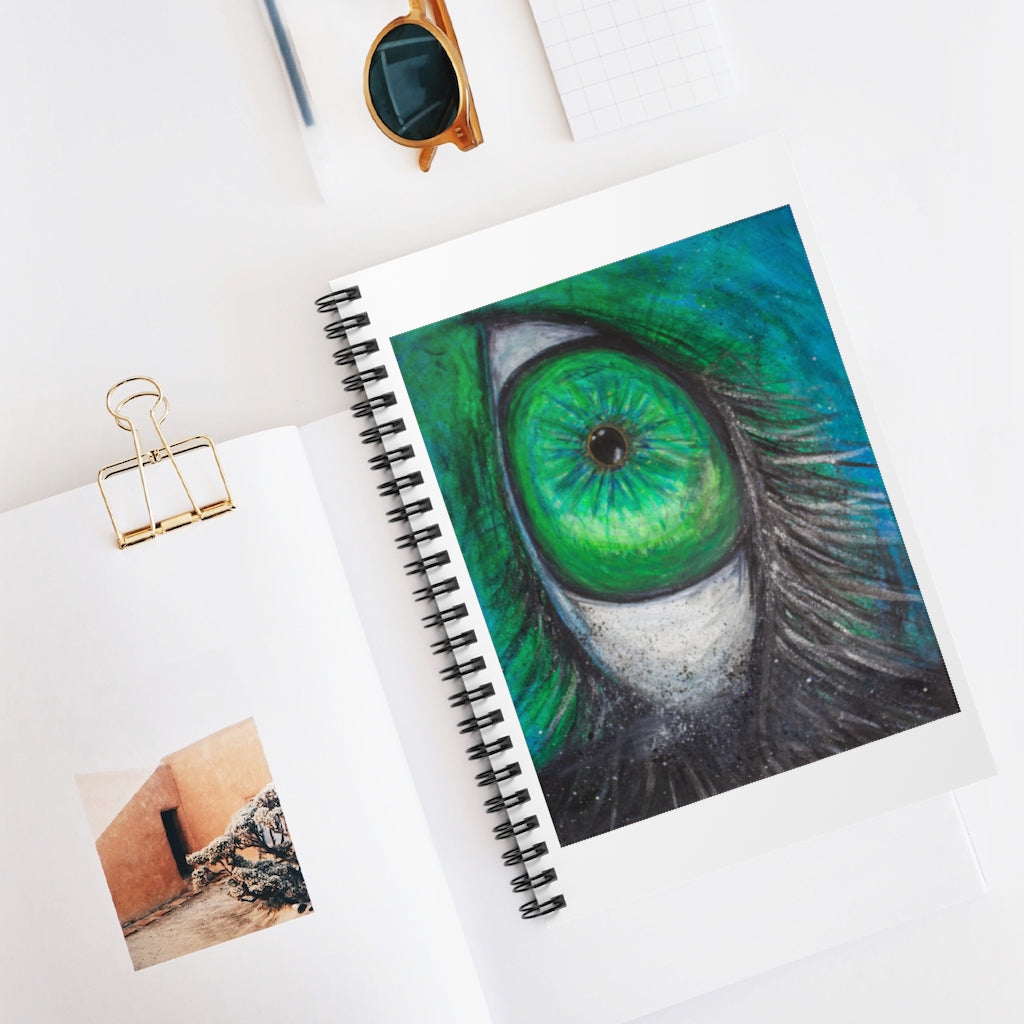 a spiral notebook with a drawing of a green eye.	