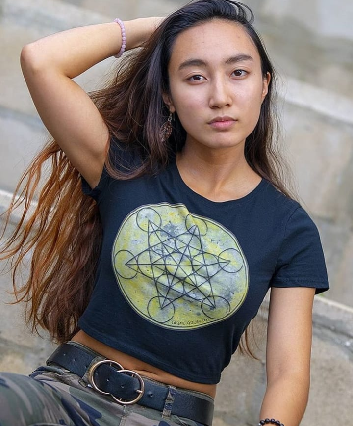 a woman with long hair wearing a black crop top with geometric design.	