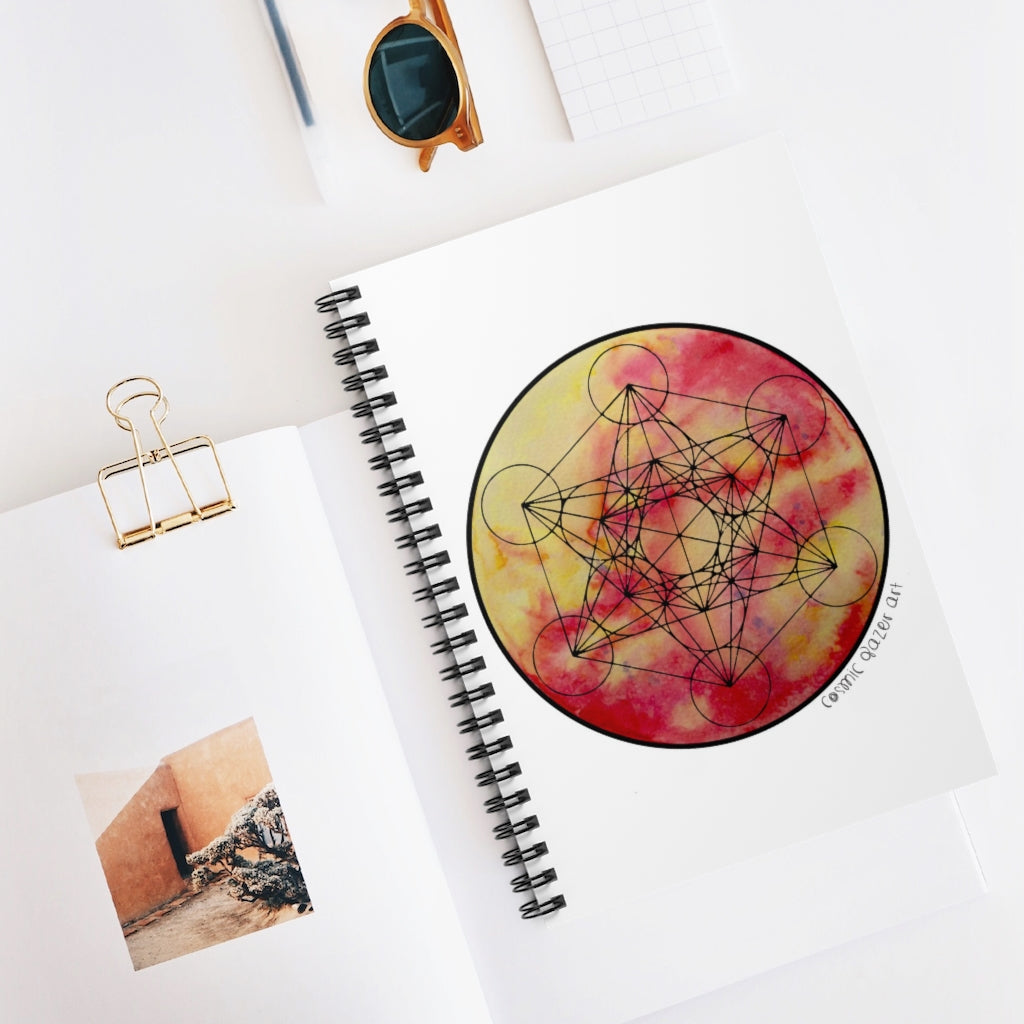 a spiral notebook with a sun painting and geometric design in the center.	