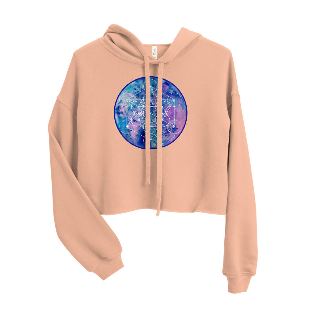 a peach crop top hoodie with a blue and purple galaxy sacred geometry print on it.